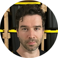 Portrait of Vitaliy, founder of SnapSort AI, with curly hair and beard, standing in front of stacked storage bins